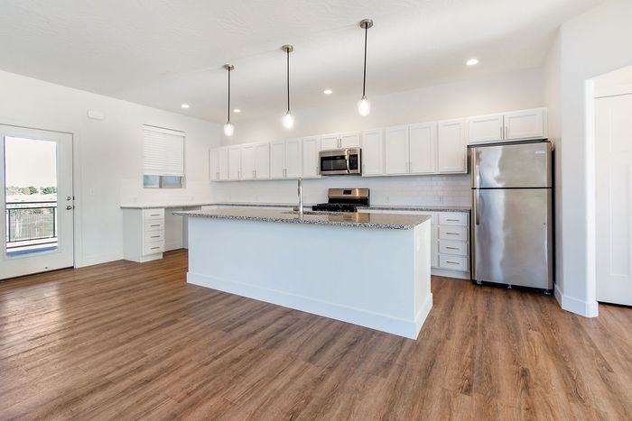 Modern kitchen design with sleek granite countertops, stainless steel appliances, and elegant pendant lighting.