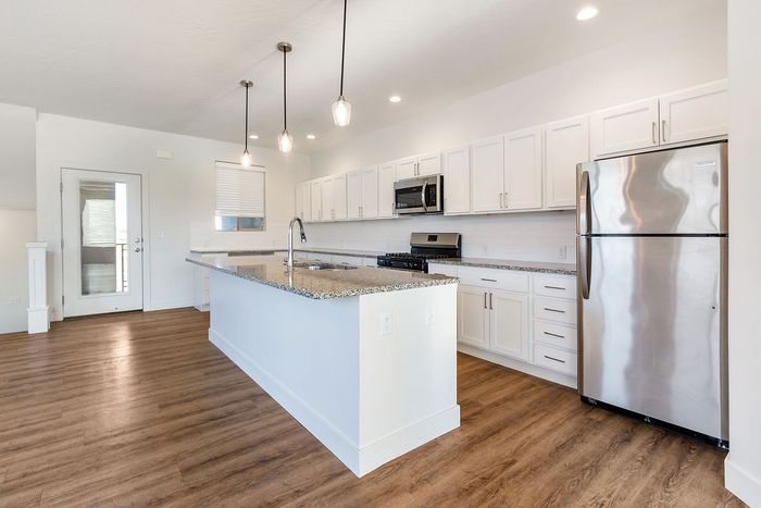 Modern kitchen with sleek granite countertops, stainless steel appliances, and elegant pendant lighting, offering a stylish and functional cooking space.