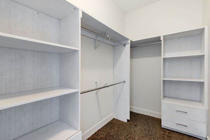 Spacious walk-in closet with modern white shelving and ample storage space.
