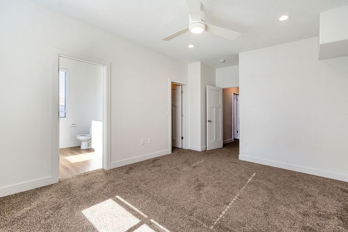 Bright, spacious bedroom with plush carpeting and an ensuite bathroom, ideal for luxurious living.