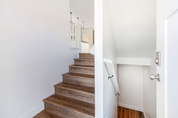 Inviting entryway with elegant wooden staircase and modern lighting, leading to a bright and airy living space.