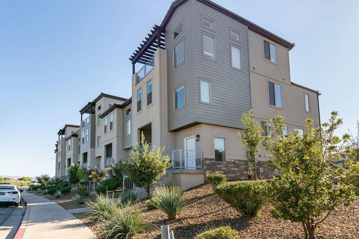 Modern apartment building exterior with sleek design and well-maintained landscaping under a clear blue sky.