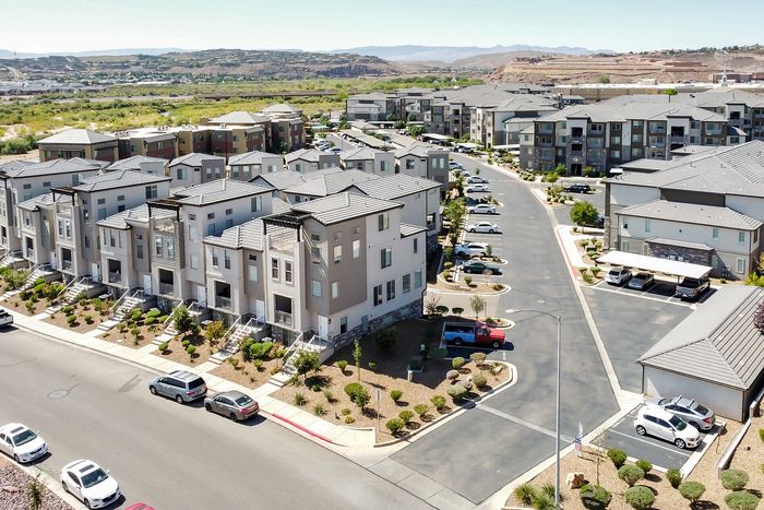 Vibrant aerial view of a modern apartment complex surrounded by lush landscaping and scenic hills, offering a glimpse into upscale suburban living.
