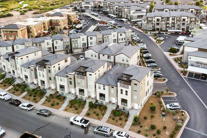Aerial view of a modern apartment complex, showcasing stylish townhouses with sleek architecture, ample parking, and landscaped green spaces in a peaceful neighborhood setting.