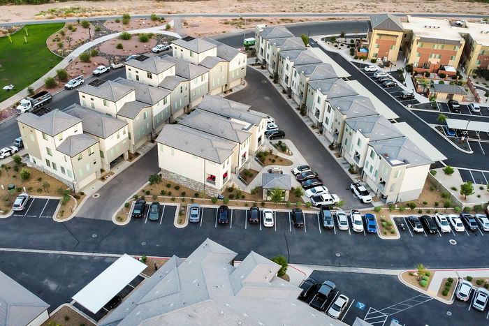 Aerial view of a modern apartment complex featuring stylish multi-story buildings with ample parking and landscaped surroundings.