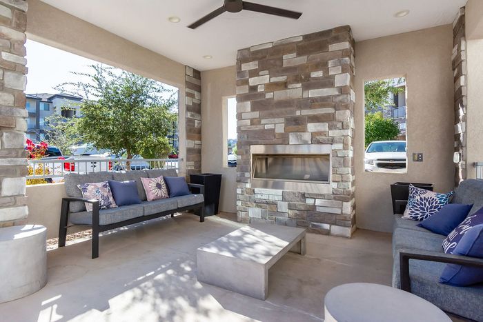 Chic outdoor patio with stone fireplace, stylish seating, and vibrant cushions creating a cozy retreat.