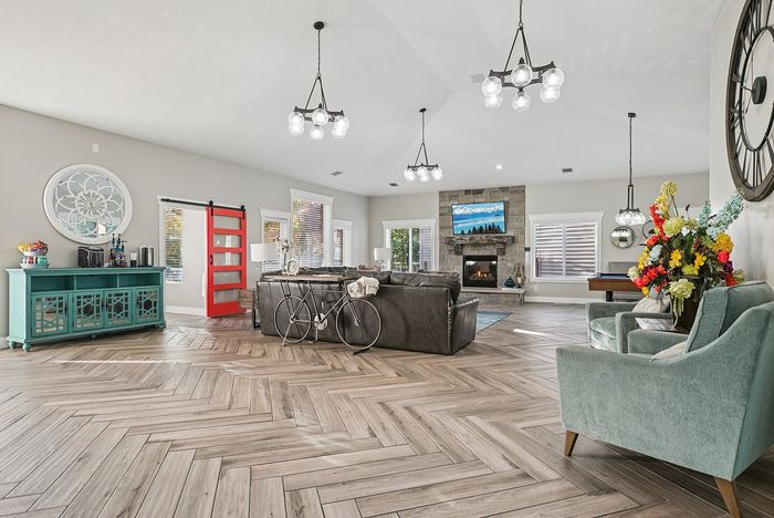 Sophisticated open-concept living room featuring elegant decor, modern lighting, a vibrant red sliding door, and a cozy fireplace setting.