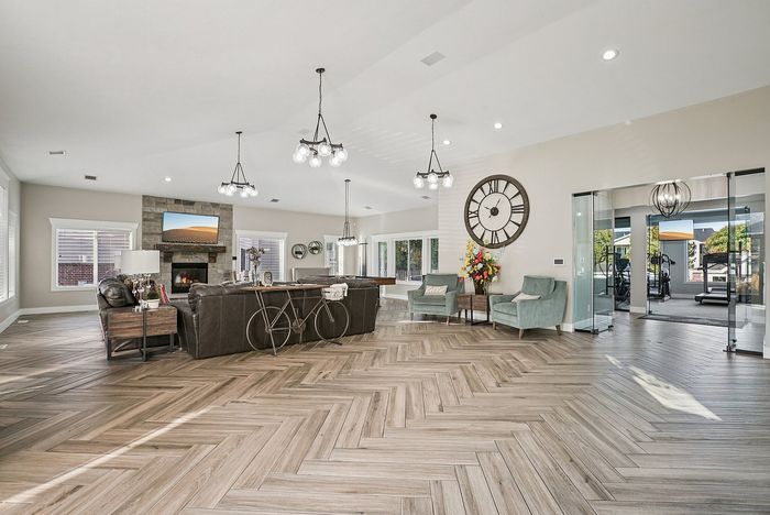 Stunning open-concept living room with elegant herringbone floors, chic lighting, and a cozy fireplace, perfect for entertaining.