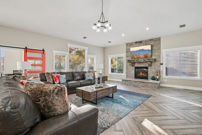 Elegant living room with a cozy stone fireplace, sleek leather sofas, and chic decor, featuring large windows that invite natural light.