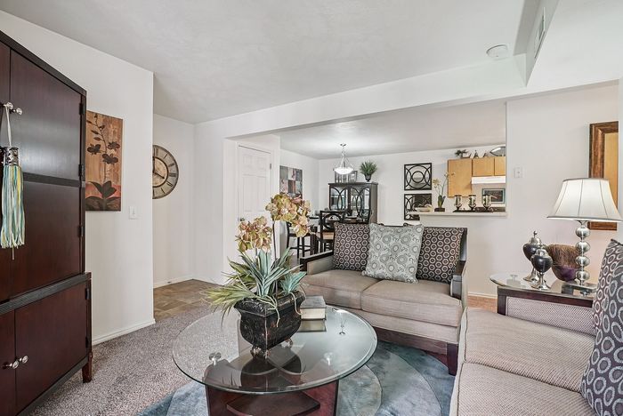 Elegant living room showcasing a modern interior design with plush seating, glass coffee table, and decorative accents, leading into a stylish dining area.