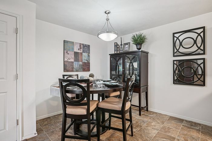Elegant dining area with modern decor, featuring a stylish round table set for four under a chic chandelier.