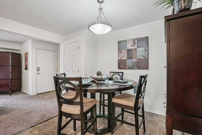 Elegant dining area with contemporary round table set for four, under a stylish light fixture, showcasing modern design and cozy ambiance.