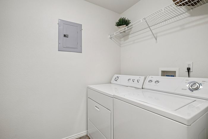 Chic laundry room with modern washer and dryer, featuring a sleek white aesthetic and efficient organization.