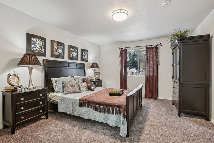 Elegant bedroom featuring a luxurious bed with plush pillows, dark wood furniture, and decorative wall art, creating a cozy and inviting atmosphere.