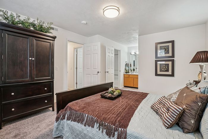 Charming bedroom with elegant dark wood wardrobe, cozy bed with decorative pillows, and ensuite bathroom access, perfect for relaxation.