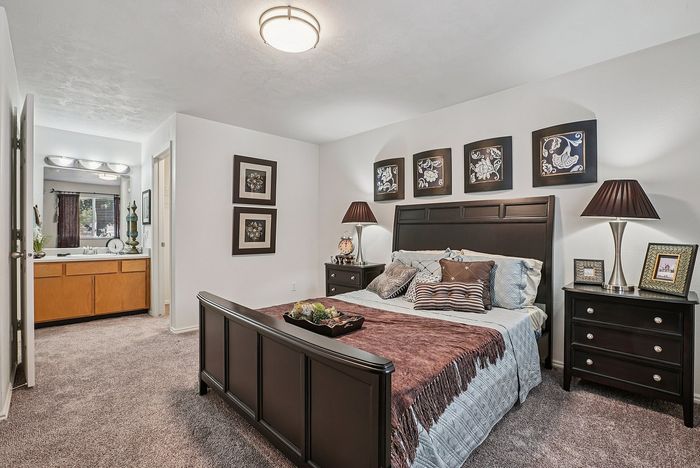 Inviting bedroom featuring a cozy bed with elegant decor, stylish artwork, and a charming vanity area with natural light.