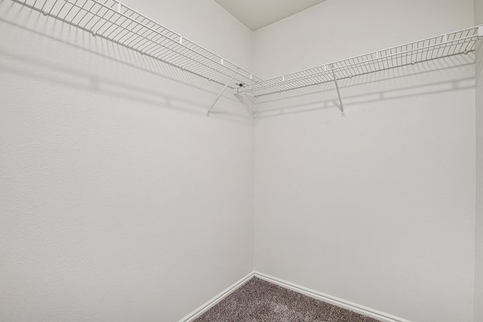 Spacious walk-in closet with sleek double shelves and plush carpet, perfect for organization and style.