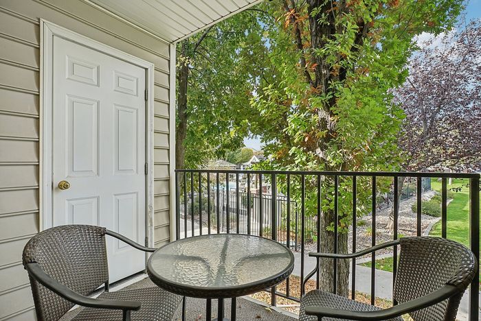 Charming balcony view with cozy seating overlooking lush greenery, perfect for relaxing outdoors.