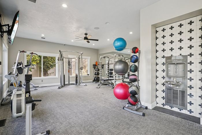 Modern apartment gym with state-of-the-art equipment, exercise balls, and a stylish hydration station, perfect for an active lifestyle.