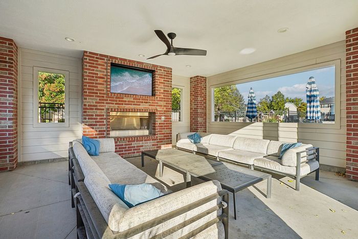 Inviting outdoor lounge with modern sofas, brick fireplace, and vibrant garden views, perfect for relaxation and entertaining.