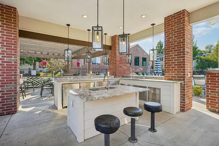 Chic outdoor kitchen with elegant pendant lights, granite countertops, and stylish bar seating, perfect for entertaining.