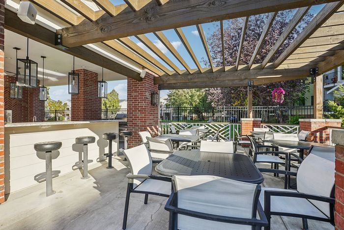 Charming outdoor patio with elegant pergola, stylish bar seating, and lush greenery for a delightful dining experience.
