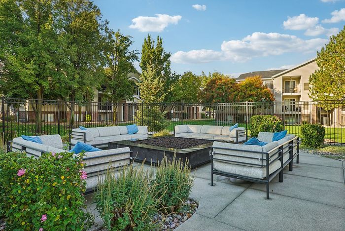 Inviting apartment complex courtyard with modern outdoor seating, lush greenery, and a sunny ambiance.