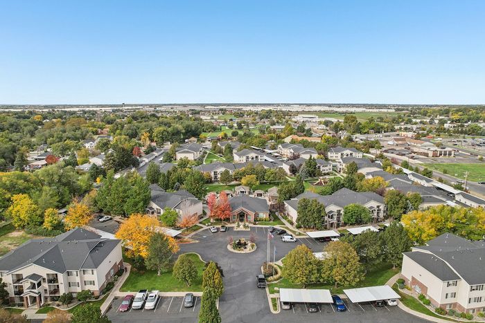 Aerial view of a picturesque residential community with tree-lined streets, beautifully landscaped gardens, and modern apartment buildings, offering a serene and vibrant living environment.