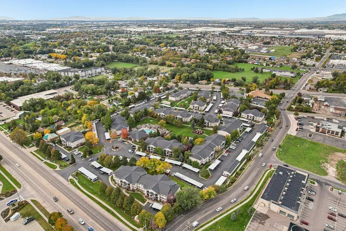 Vibrant aerial view of a modern apartment complex surrounded by lush greenery, showcasing a scenic blend of urban development and natural beauty.