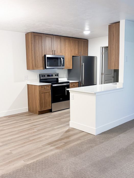 A beautifully updated kitchen featuring stainless steel appliances, wood-grain cabinetry, and expansive counter space.