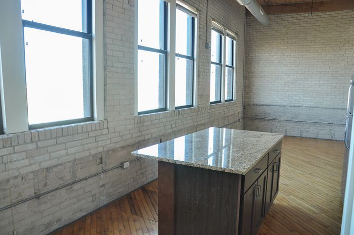 Bright industrial-style kitchen with a marble island countertop and expansive windows.