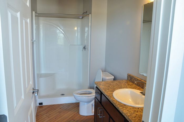 Elegant bathroom featuring a granite countertop, modern sink, and spacious shower area with wooden flooring.