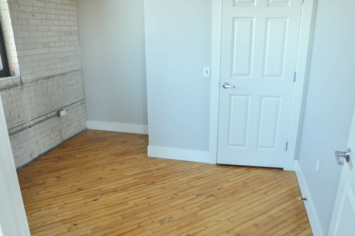 Bright and charming room with elegant hardwood floors and a rustic brick accent wall, perfect for a cozy living space.