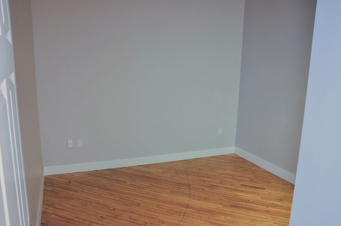 Bright room with elegant wooden flooring and soft gray walls, ideal for a home office or cozy guest bedroom.