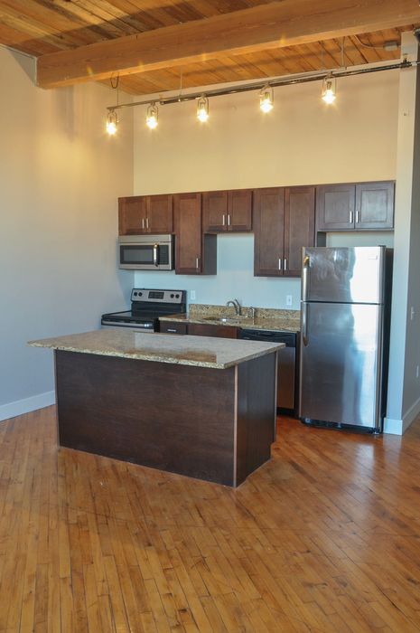 Modern kitchen with sleek dark wood cabinets, stainless steel appliances, and elegant lighting on polished hardwood floors.