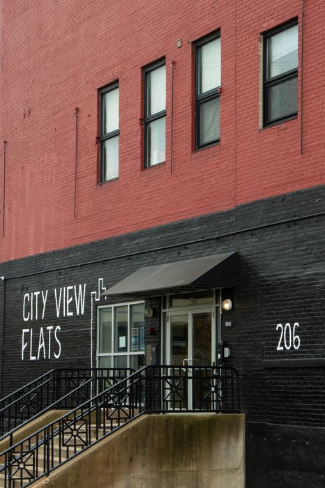 Chic urban entrance at City View Flats with modern black and red brick design, welcoming steps, and stylish awning at 206.