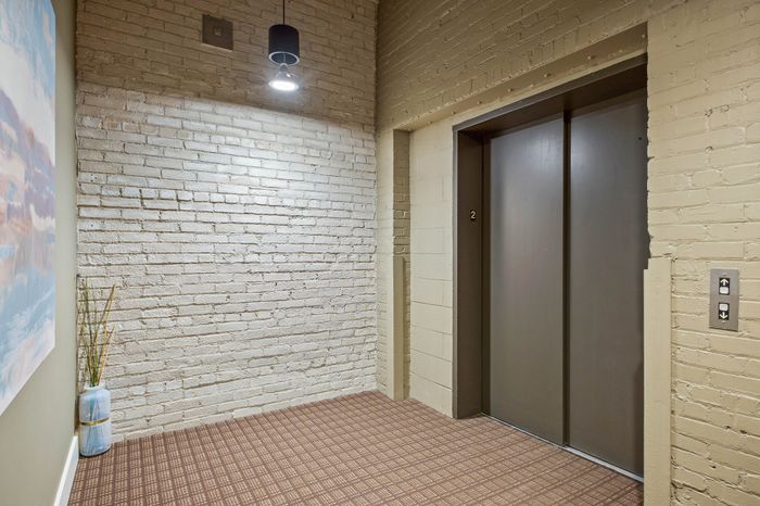 Charming apartment lobby with stylish exposed brick walls, cozy lighting, and a sleek elevator.