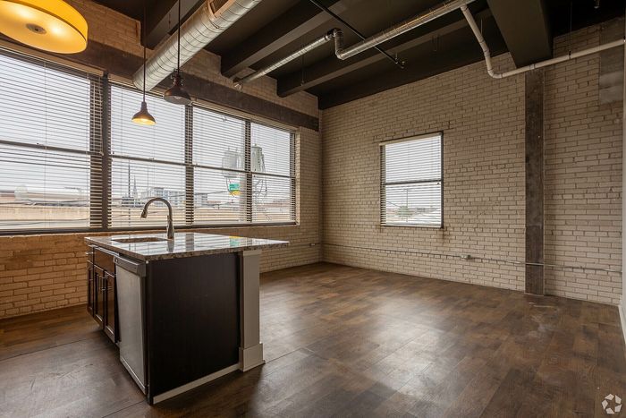 Chic industrial-style loft with exposed brick walls, large windows, and a modern kitchen island.