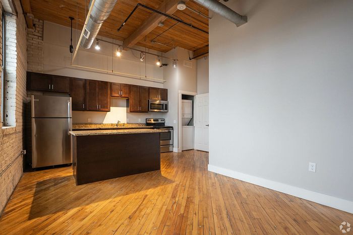 Chic industrial loft-style kitchen with stainless steel appliances, exposed brick, and warm hardwood floors.