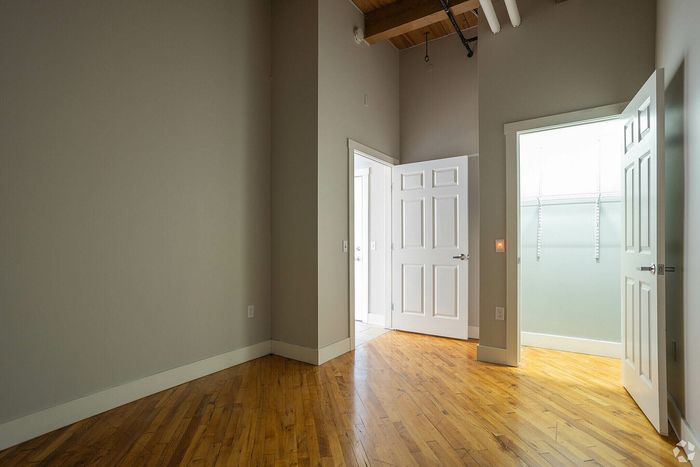 Bright and spacious room with natural wood flooring, high ceilings, and ample closet space, perfect for modern living.