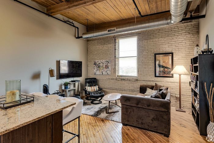 Chic urban apartment living room with exposed brick walls, stylish furnishings, and a cozy open layout.