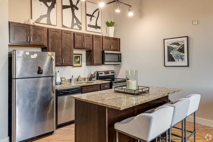 Elegant kitchen with sleek stainless steel appliances, granite countertops, and chic bar seating, creating a modern and inviting space.