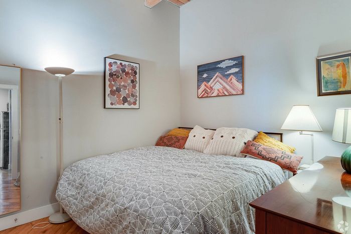 Cozy and stylish bedroom with modern decor, featuring a comfortable bed with patterned bedding and vibrant throw pillows.