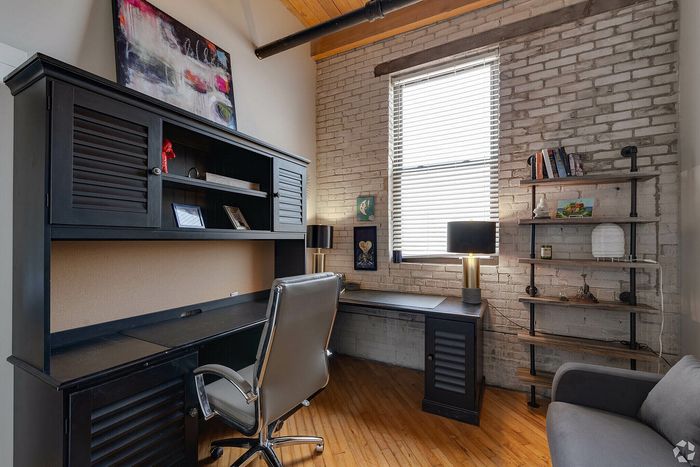 Chic home office with brick walls, elegant dark furniture, and a modern touch lamp, perfect for a productive environment.