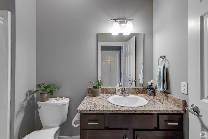 Contemporary bathroom featuring granite countertops, sleek sink, and modern lighting with elegant decor accents.