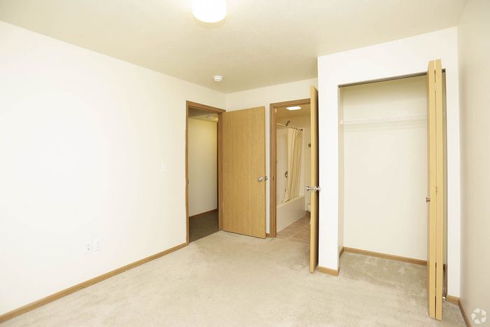 Bright and cozy bedroom with plush carpet, dual closets, and an ensuite bathroom, offering convenient and stylish living space.