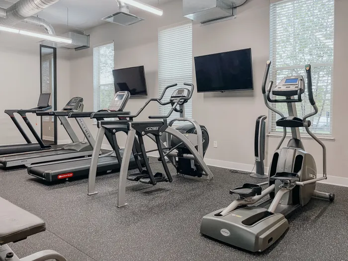 Contemporary gym with state-of-the-art exercise machines including treadmills, elliptical, and flat-screen TVs.