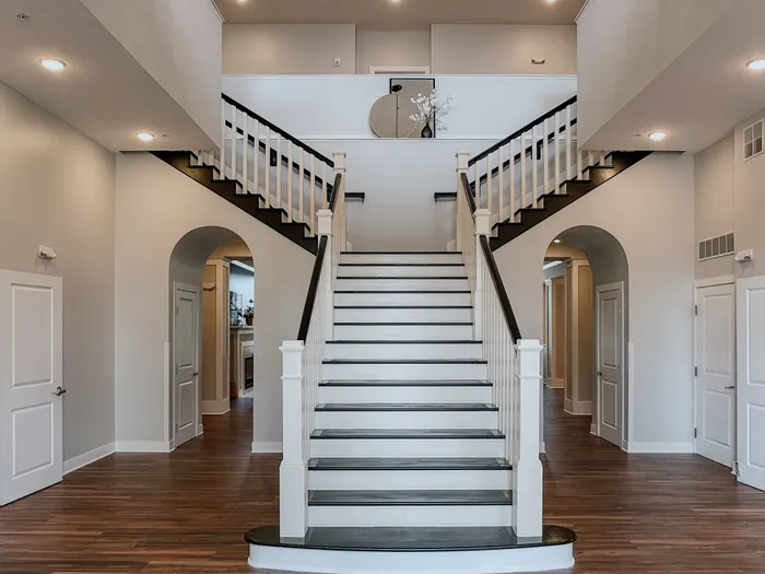 Spacious foyer featuring a grand staircase with wooden railings and pristine flooring.