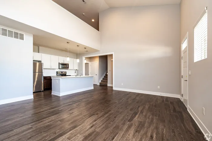 Spacious open-concept living area featuring a modern kitchen with stainless steel appliances and elegant wood flooring.