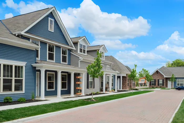 Beautiful suburban street featuring elegant blue and brick homes with a clear blue sky.